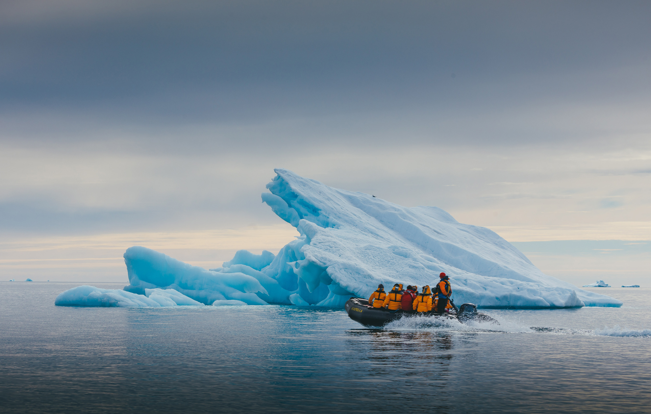 Zodaic-ride-past-iceberg-in-Svalbard-Quark people in zodiac by iceberg in svalbard