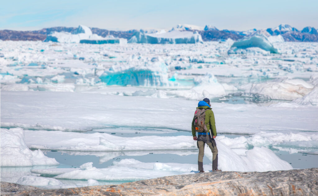 a hiker in Greenland overlooking the ice fjord