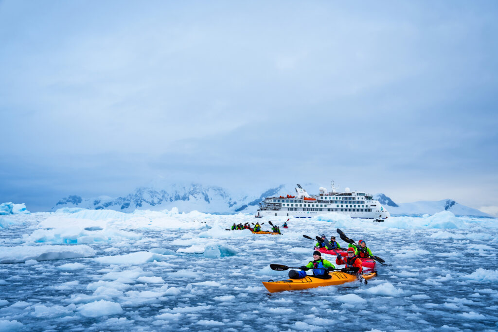 greg mortimer expedition ship with kayakers in the foreground