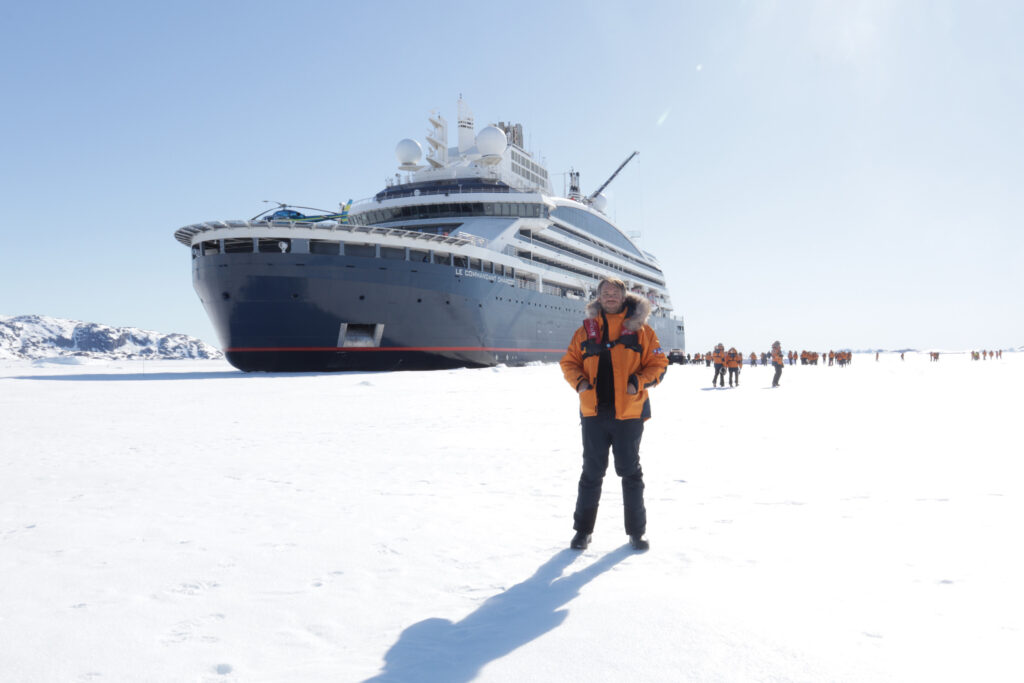 a person standing on the sea ice next to le Commandant Charcot icebreaker ship